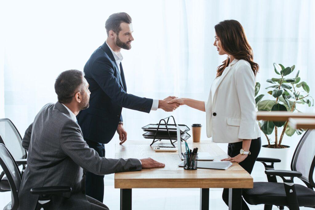 beautiful advisor and investor in suits shaking hands at office